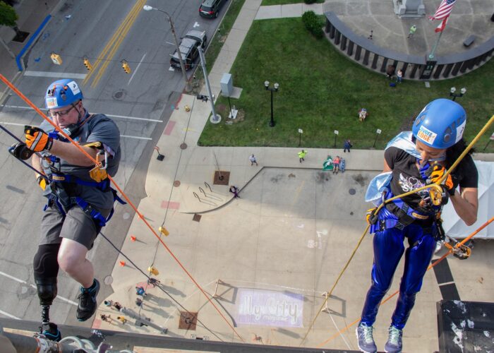 Tom Brannon and Mary Delgado wearing a cape start to go Over the Edge.