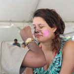 A young woman has her face painted. It is ADA Day 2019.